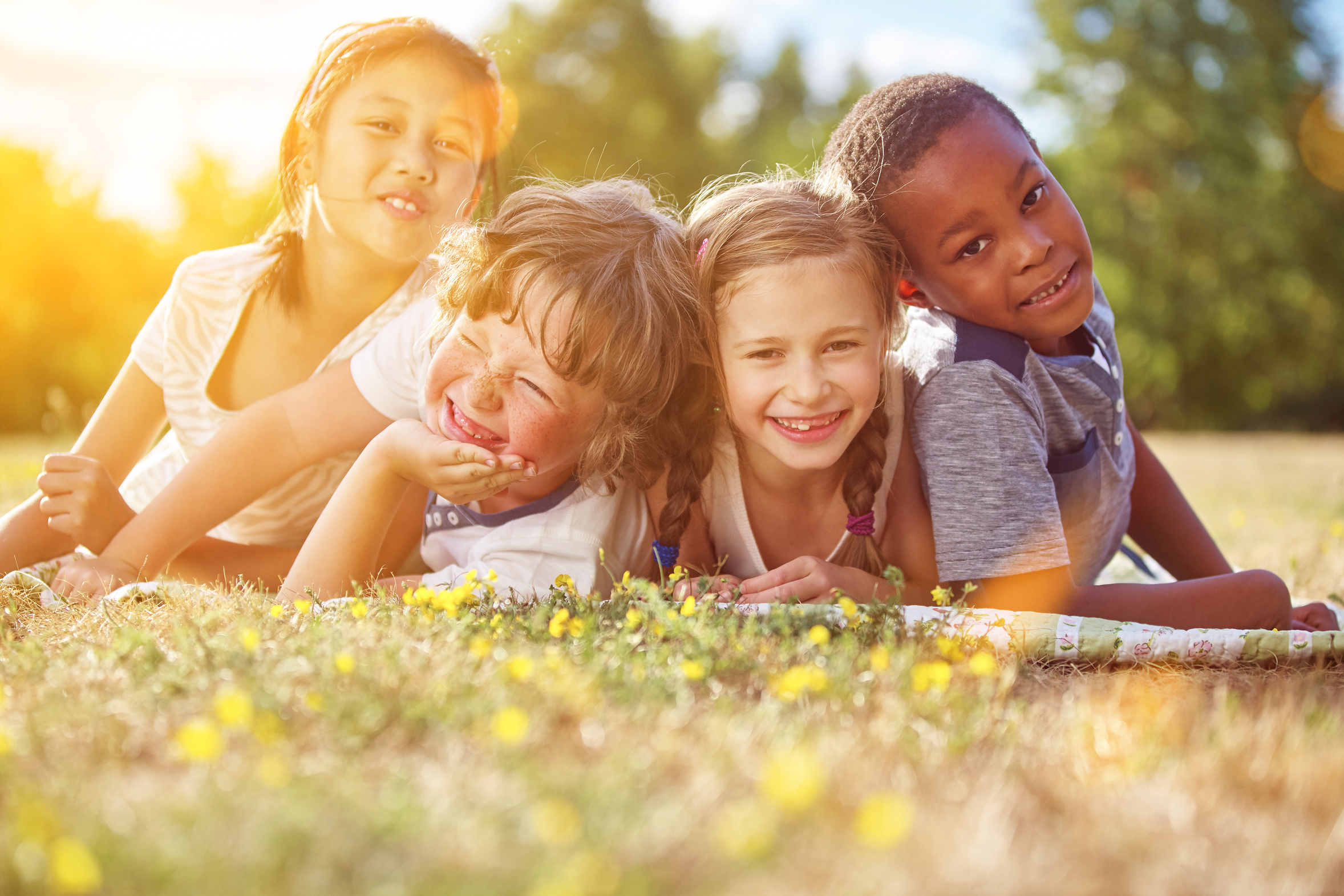Multikulturelle Gruppe Kinder im Sommer liegt glücklich im Gras