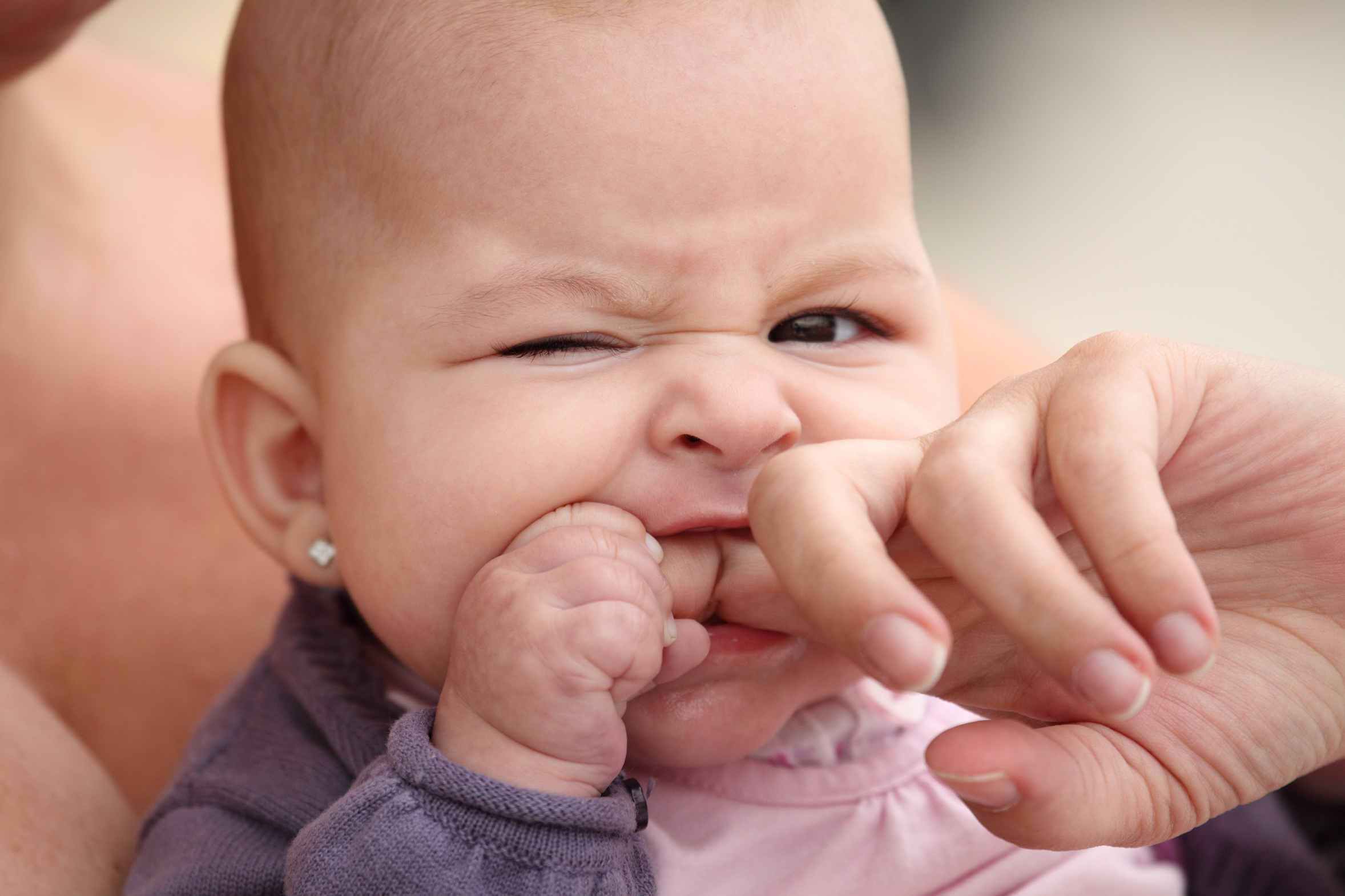 little baby biting her mother finger